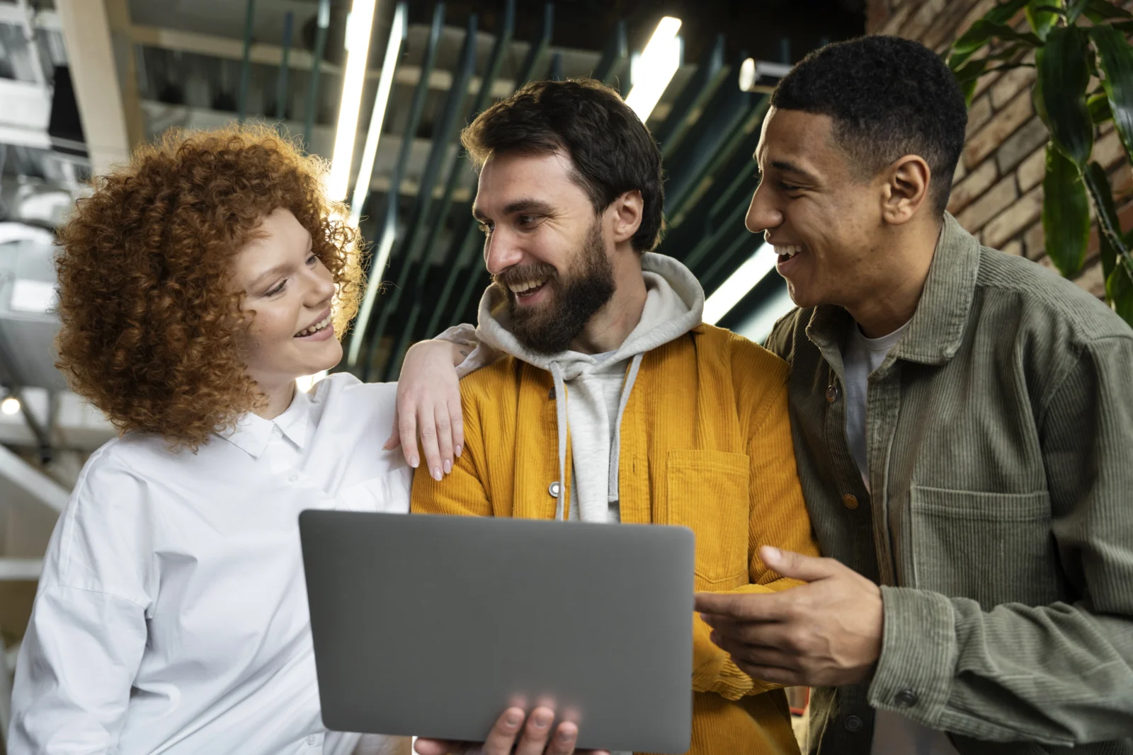 Trois collaborateurs réunis autour d’un ordinateur portable en espace de travail moderne, illustrant la collaboration, le travail d’équipe et l’échange en environnement professionnel