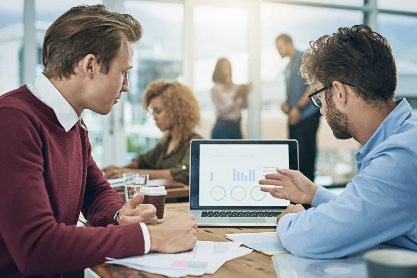 Deux collaborateurs analysant des graphiques sur ordinateur portable lors d’une réunion, illustrant le pilotage des performances et l’utilisation d’un CRM en entreprise