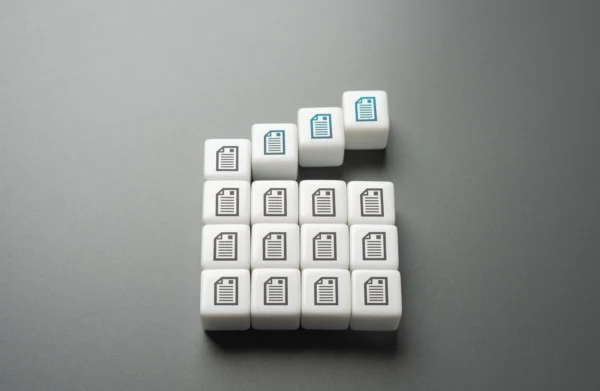 Cubes blancs avec pictogrammes de documents empilés en pyramide avec mise en avant progressive, illustrant la gestion documentaire, la structuration des données et la hiérarchisation de l’information en entreprise