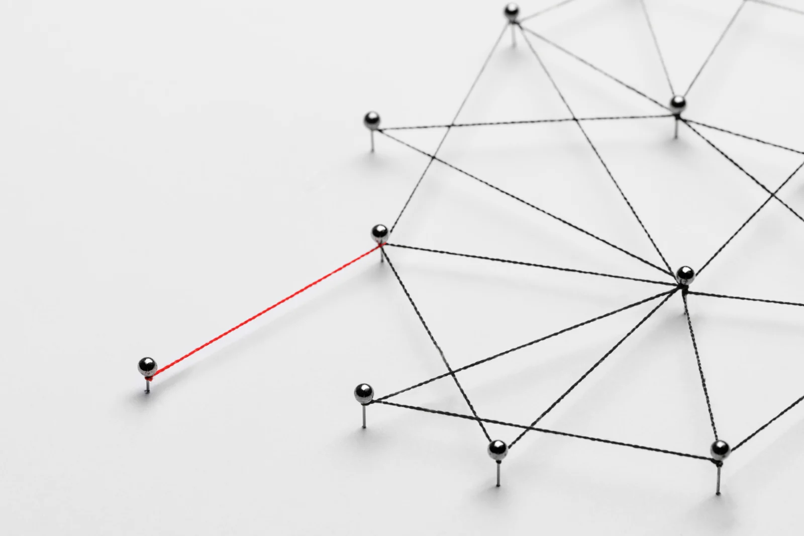 Réseau de points métalliques reliés par des fils formant une structure avec une connexion en rouge, illustrant la connectivité, les réseaux de données et l’interconnexion des systèmes